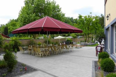Parking extérieur vide avec un seul véhicule blanc, entouré de végétation et d'un mur en pierre.