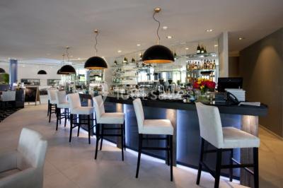 Salle de réunion moderne avec table rectangulaire, chaises noires, écran mural, tableau blanc et minibar.
