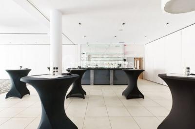 Salle de réunion moderne avec table rectangulaire, chaises noires, écran mural, tableau blanc et minibar.