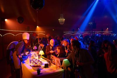 Un acrobate réalise une figure sur un tissu aérien sous un chapiteau éclairé par des lumières colorées.