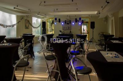 Salle lumineuse avec une table en métal, des fenêtres et une porte jaune donnant sur l'extérieur.