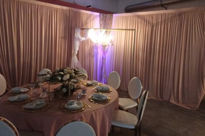 Salle vide avec parquet, murs clairs, table en métal, miroir mural et lumière naturelle entrant par une fenêtre.