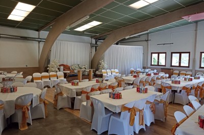 Salle vide avec parquet, murs clairs, table en métal, miroir mural et lumière naturelle entrant par une fenêtre.