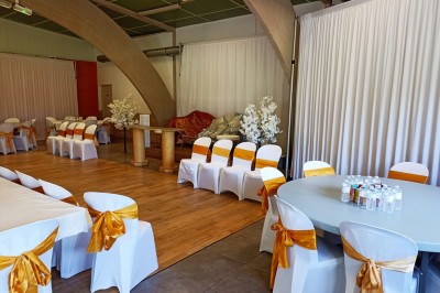 Salle vide avec parquet, murs clairs, table en métal, miroir mural et lumière naturelle entrant par une fenêtre.