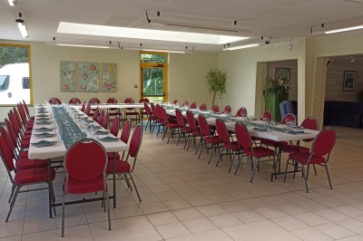 Salle vide avec parquet, murs clairs, table en métal, miroir mural et lumière naturelle entrant par une fenêtre.