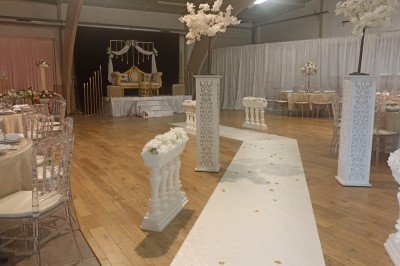 Salle vide avec parquet, murs clairs, table en métal, miroir mural et lumière naturelle entrant par une fenêtre.