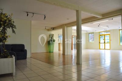 Salle lumineuse avec une table en métal, des fenêtres et une porte jaune donnant sur l'extérieur.