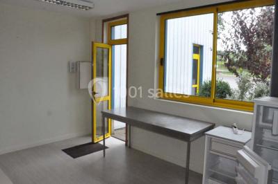 Salle lumineuse avec une table en métal, des fenêtres et une porte jaune donnant sur l'extérieur.