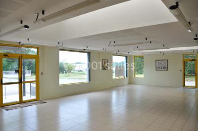 Salle lumineuse avec une table en métal, des fenêtres et une porte jaune donnant sur l'extérieur.
