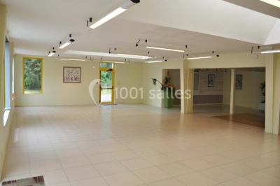 Salle lumineuse avec une table en métal, des fenêtres et une porte jaune donnant sur l'extérieur.