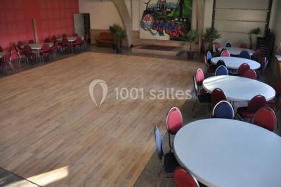 Salle lumineuse avec une table en métal, des fenêtres et une porte jaune donnant sur l'extérieur.