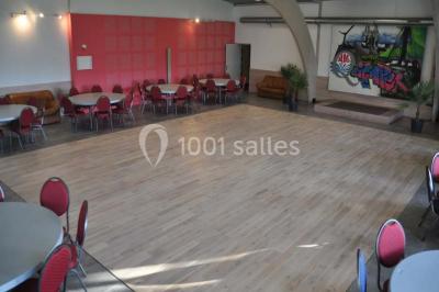Salle lumineuse avec une table en métal, des fenêtres et une porte jaune donnant sur l'extérieur.