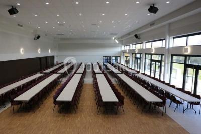 Cuisine professionnelle avec plans de travail en inox, casseroles, assiettes empilées et équipements de restauration.