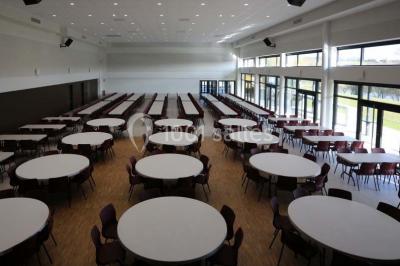 Cuisine professionnelle avec plans de travail en inox, casseroles, assiettes empilées et équipements de restauration.