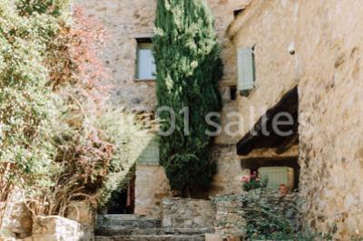 Des personnes discutent autour d'une table en tonneau, partageant des viennoiseries dans un cadre extérieur verdoyant.