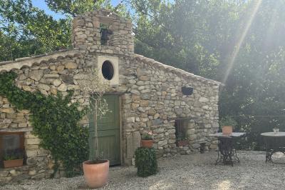 Des personnes discutent autour d'une table en tonneau, partageant des viennoiseries dans un cadre extérieur verdoyant.