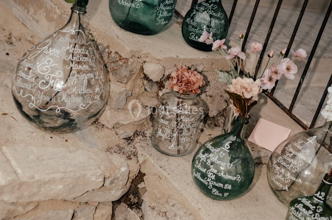 Vases en verre transparent et vert décorés de calligraphies blanches, disposés sur des marches en pierre.