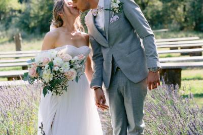 Des personnes discutent autour d'une table en tonneau, partageant des viennoiseries dans un cadre extérieur verdoyant.