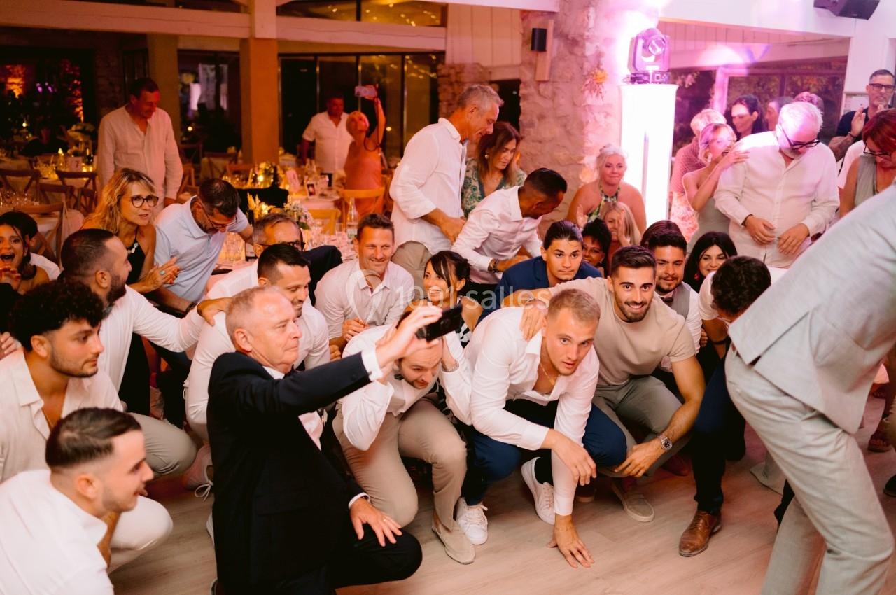 Groupe de personnes souriantes posant ensemble dans une ambiance festive et lumineuse lors d'un événement en intérieur.