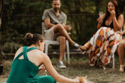 Des personnes discutent autour d'une table en tonneau, partageant des viennoiseries dans un cadre extérieur verdoyant.