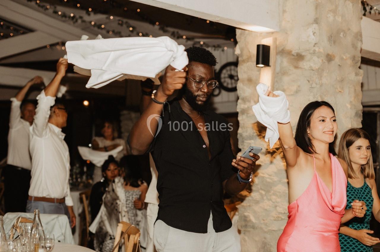 Des personnes dansent et agitent des serviettes blanches dans un lieu festif avec une ambiance chaleureuse.