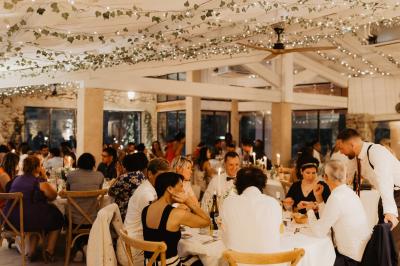 Des personnes discutent autour d'une table en tonneau, partageant des viennoiseries dans un cadre extérieur verdoyant.