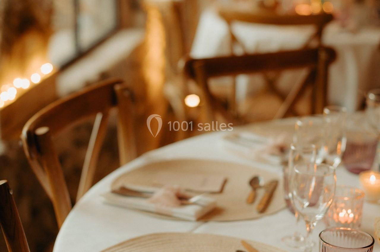 Table dressée avec élégance, comprenant assiettes, couverts, serviettes nouées et verres, dans une ambiance chaleureuse.