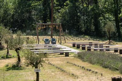 Des personnes discutent autour d'une table en tonneau, partageant des viennoiseries dans un cadre extérieur verdoyant.