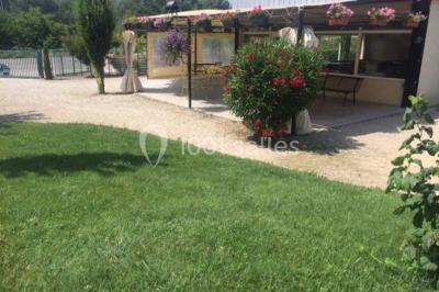 Allée en gravier bordée de pelouse et d'arbustes, menant vers un espace verdoyant.