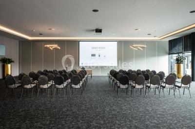 Bornes de recharge électriques Tesla alignées sur un parking, entourées de végétation et de voitures en arrière-plan.