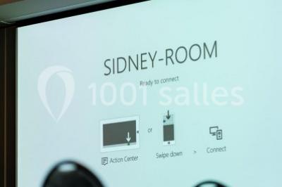 Bornes de recharge électriques Tesla alignées sur un parking, entourées de végétation et de voitures en arrière-plan.