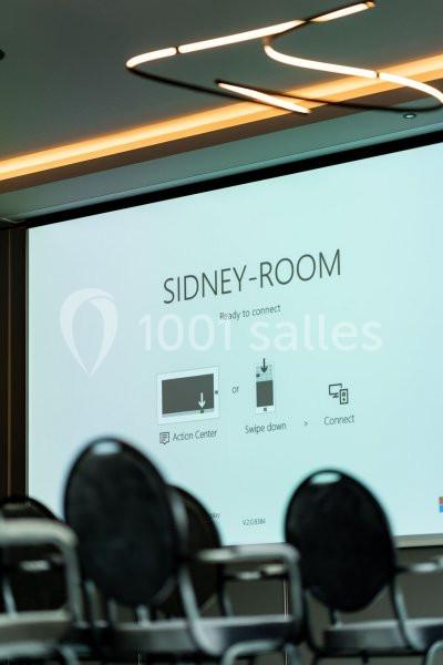 Écran de présentation dans une salle de réunion, affichant des instructions de connexion pour des appareils.