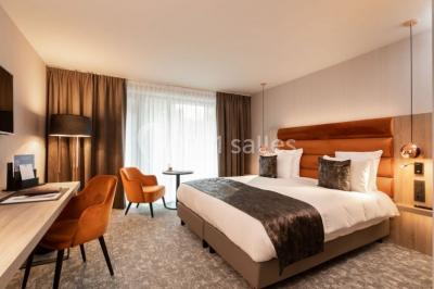 Bornes de recharge électriques Tesla alignées sur un parking, entourées de végétation et de voitures en arrière-plan.