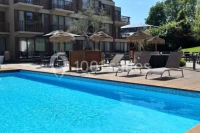 Bornes de recharge électriques Tesla alignées sur un parking, entourées de végétation et de voitures en arrière-plan.