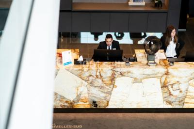 Bornes de recharge électriques Tesla alignées sur un parking, entourées de végétation et de voitures en arrière-plan.