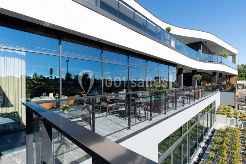 Façade moderne d'un bâtiment avec grandes baies vitrées et balcons aménagés donnant sur un espace extérieur.