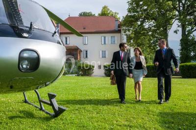 Un grand groupe de personnes en t-shirts verts pose joyeusement devant des véhicules stationnés en extérieur.