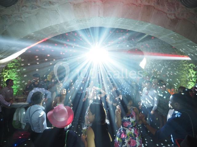 Personnes dansant sous des jeux de lumière dans une salle voûtée avec ambiance festive.