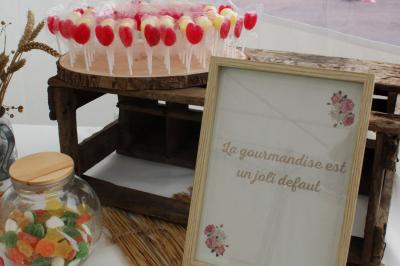 Table ronde élégamment dressée avec vaisselle, couverts, serviettes roses et centre de table floral coloré.