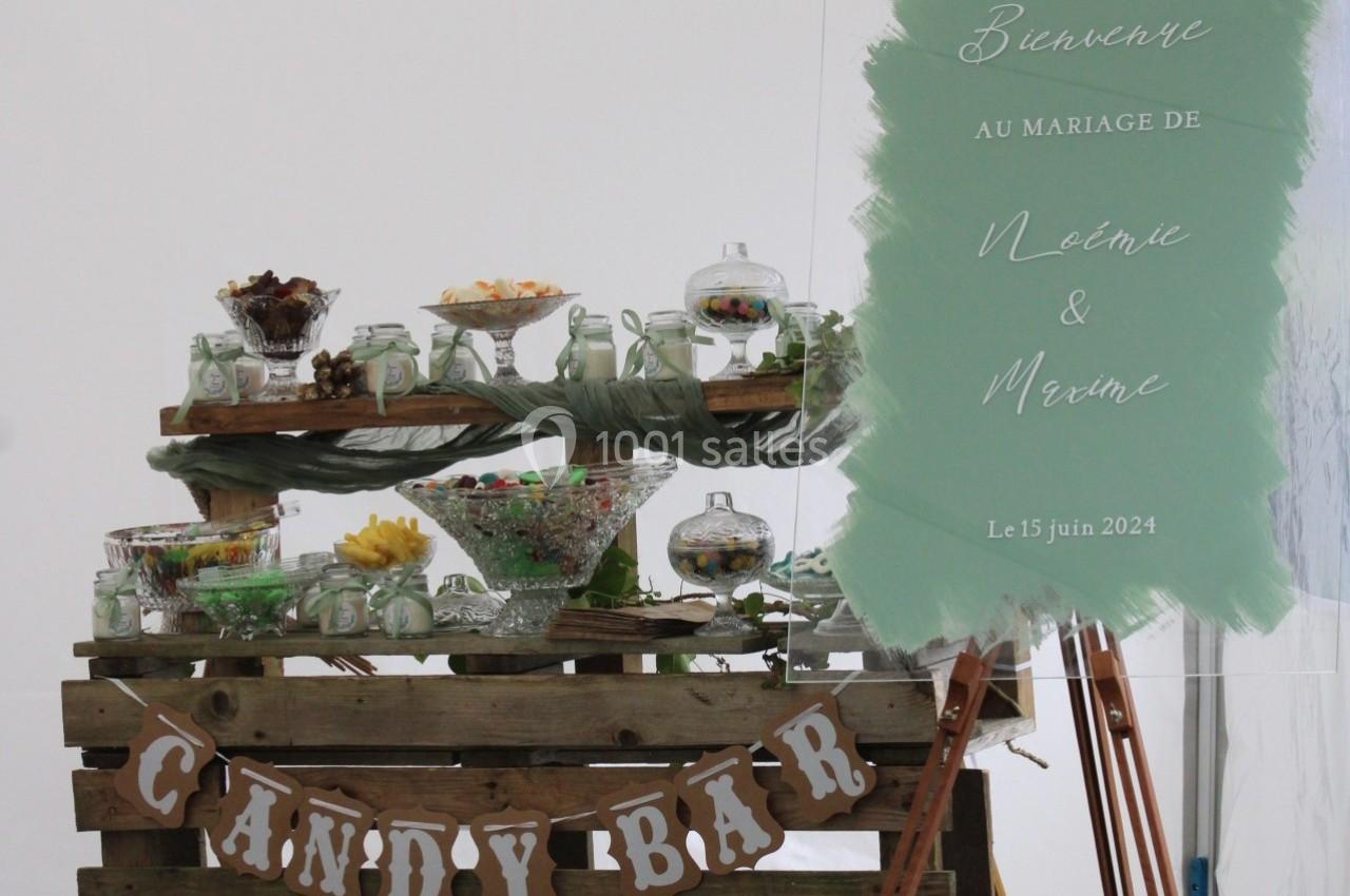 Table garnie de bonbonnières et décorations pour un candy bar, avec un panneau annonçant un mariage.
