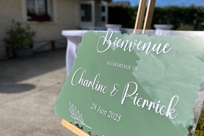Table ronde élégamment dressée avec vaisselle, couverts, serviettes roses et centre de table floral coloré.