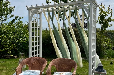 Table ronde élégamment dressée avec vaisselle, couverts, serviettes roses et centre de table floral coloré.