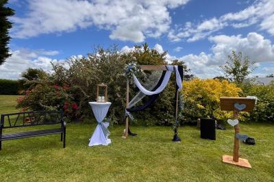 Table ronde élégamment dressée avec vaisselle, couverts, serviettes roses et centre de table floral coloré.