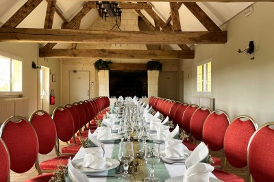 Table ronde élégamment dressée avec vaisselle, couverts, serviettes roses et centre de table floral coloré.