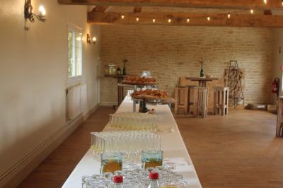 Table ronde élégamment dressée avec vaisselle, couverts, serviettes roses et centre de table floral coloré.