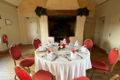 Table ronde élégamment dressée avec vaisselle, couverts, serviettes roses et centre de table floral coloré.