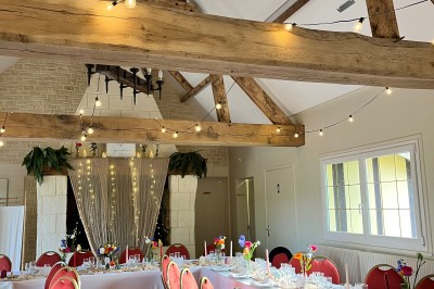 Table ronde élégamment dressée avec vaisselle, couverts, serviettes roses et centre de table floral coloré.