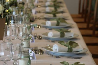 Table ronde élégamment dressée avec vaisselle, couverts, serviettes roses et centre de table floral coloré.