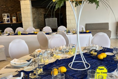 Table ronde élégamment dressée avec vaisselle, couverts, serviettes roses et centre de table floral coloré.