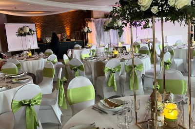 Table ronde élégamment dressée avec vaisselle, couverts, serviettes roses et centre de table floral coloré.